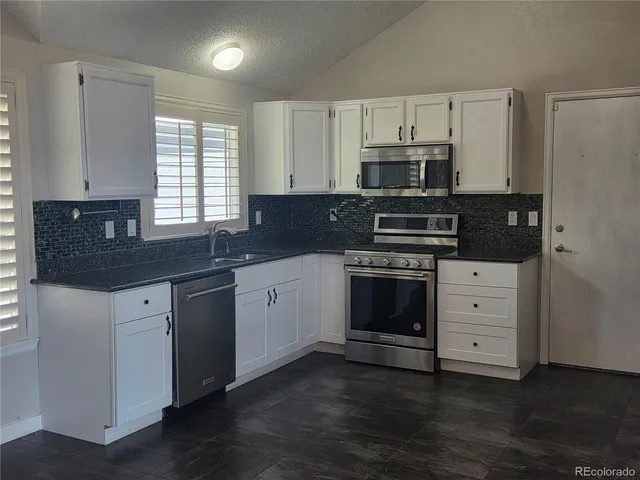 a kitchen with granite countertop a stove a sink and a microwave