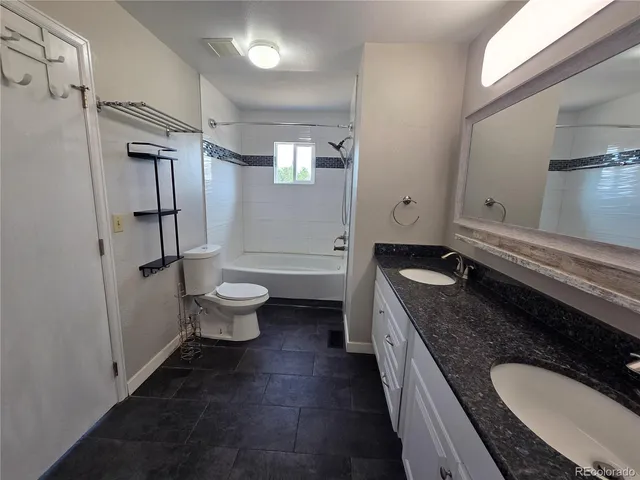 a spacious bathroom with a granite countertop sink a toilet a shower and a mirror