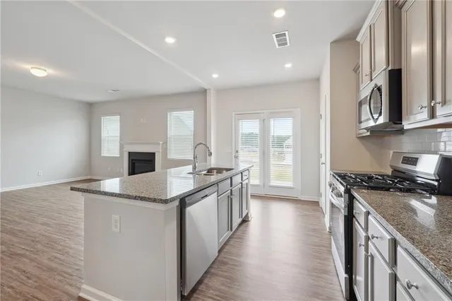 a kitchen with stainless steel appliances granite countertop a sink stove and refrigerator