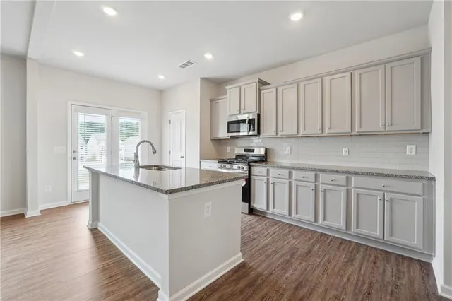 a kitchen with kitchen island granite countertop a sink appliances cabinets and wooden floor