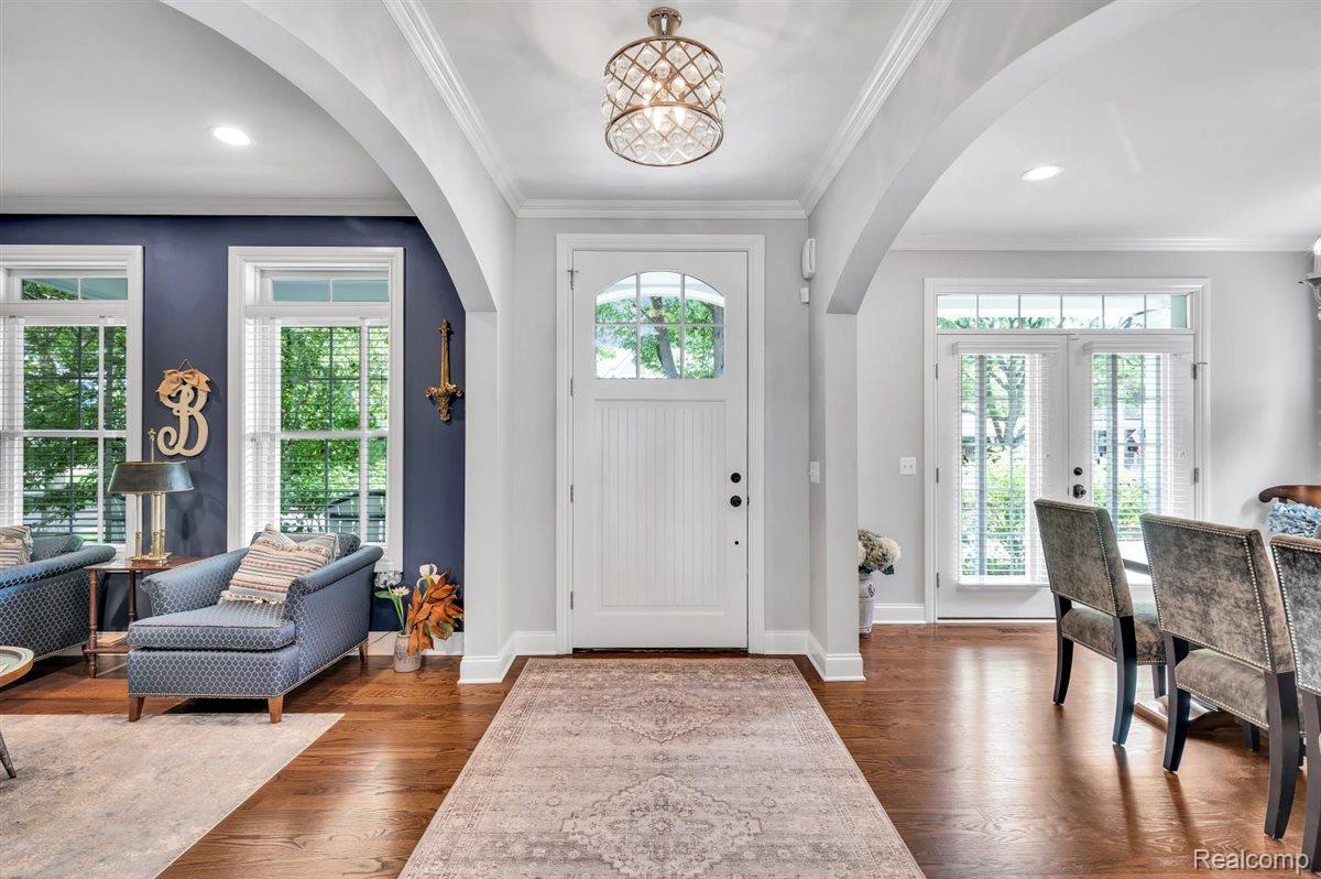 142 Griggs Street Rochester, MI 48307 - Photo 6 of 51 Entryway featuring wood-finish flooring, a white paneled door with an arched glass insert, and a decorative crystal chandelier