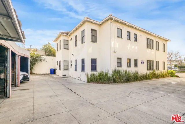 a view of a white house with a yard and potted plants