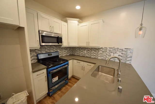 a kitchen with granite countertop a stove sink and microwave