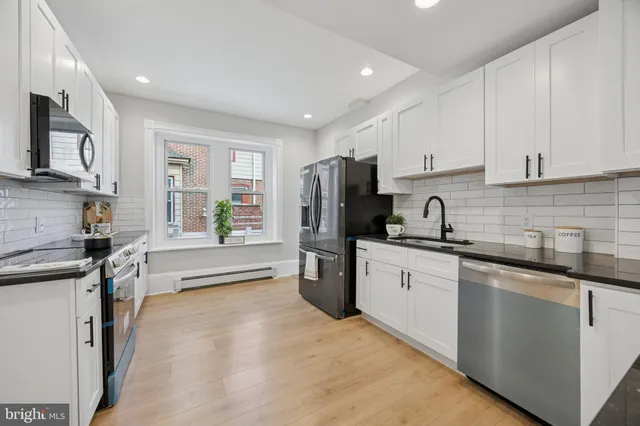 a kitchen with stainless steel appliances granite countertop a sink stove refrigerator and cabinets