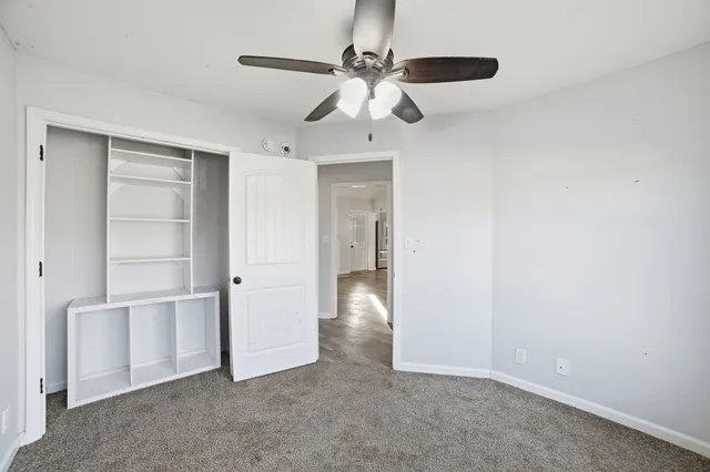 an empty room with closet and a ceiling fan