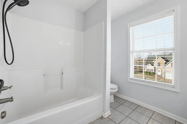 a bathroom with a bath tub a glass door shower and a window