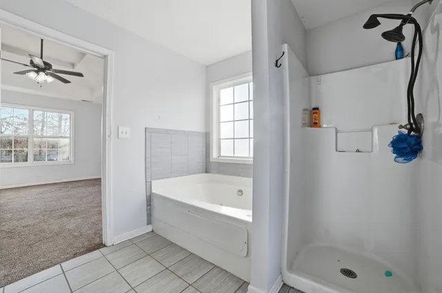 a bathroom with a bathtub a shower and a window