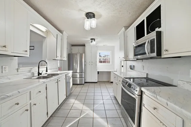 a kitchen with stainless steel appliances granite countertop a stove a sink and a microwave