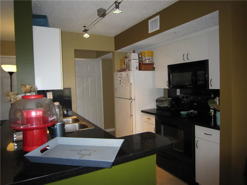 3874 Lyons Road, Unit 2036 Coconut Creek, FL 33073 - Photo 10 of 16 a kitchen with a refrigerator and a stove top open