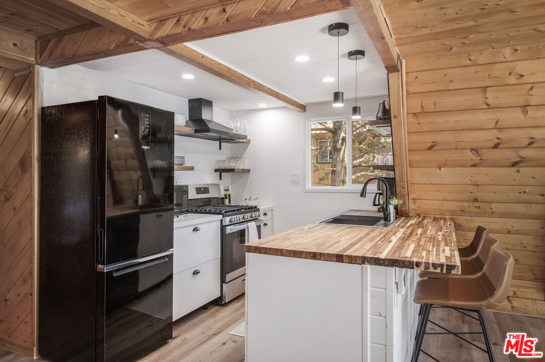 Undisclosed Address Big Bear City, CA 92314 - Photo 11 of 46 a kitchen with stainless steel appliances granite countertop a refrigerator a sink dishwasher a stove and white countertops with wooden floor