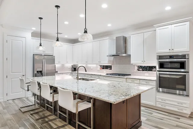 a kitchen with kitchen island granite countertop a table chairs sink and cabinets