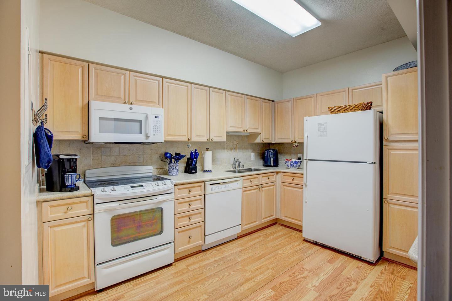 3200 North Leisure World Boulevard, Unit 911 Silver Spring, MD 20906 - Photo 8 of 39 a kitchen with white cabinets and white stainless steel appliances