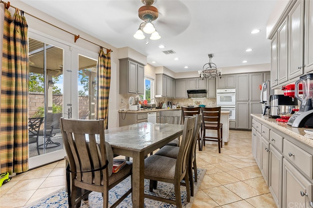 12547 Vintner Drive Rancho Cucamonga, CA 91739 - Photo 16 of 52 a kitchen with a dining table chairs and white cabinets