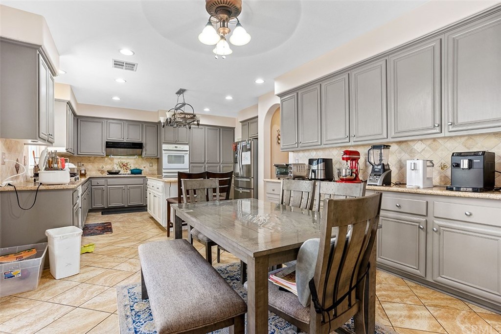 12547 Vintner Drive Rancho Cucamonga, CA 91739 - Photo 17 of 52 a kitchen with a dining table chairs and microwave