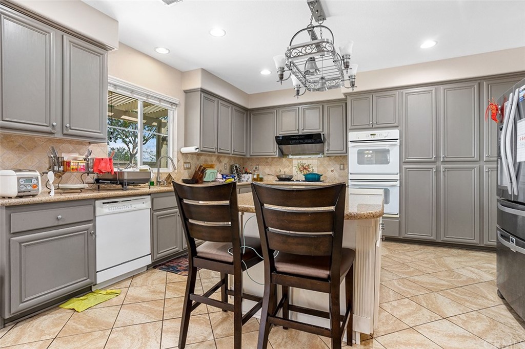12547 Vintner Drive Rancho Cucamonga, CA 91739 - Photo 18 of 52 a kitchen with stainless steel appliances a dining table chairs stove refrigerator and cabinets