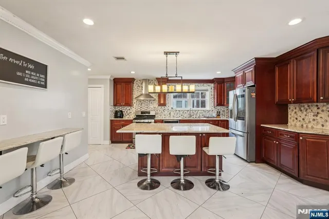 a kitchen with stainless steel appliances kitchen island granite countertop a table chairs and a refrigerator