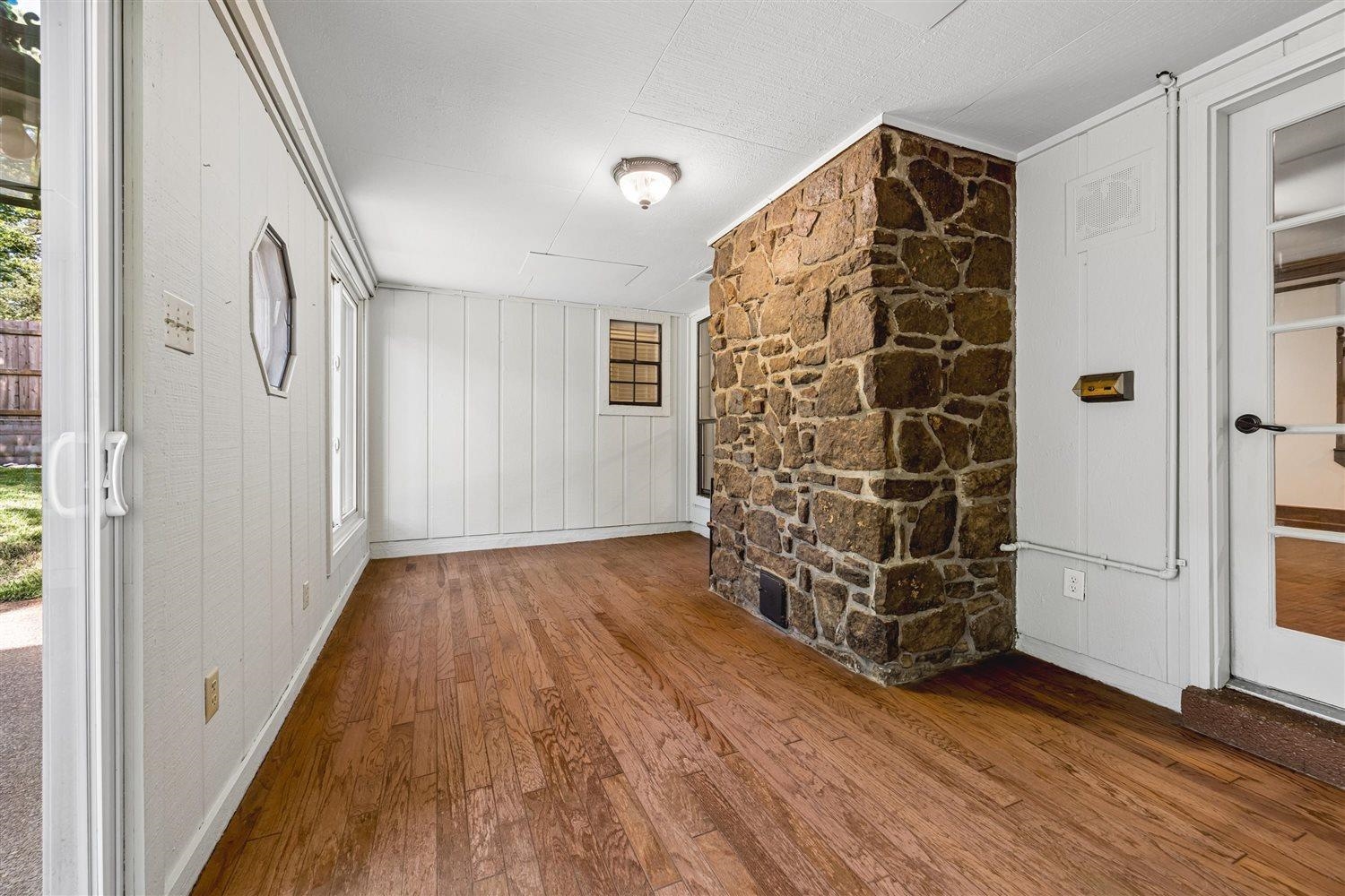 8970 Farmoor Road Germantown, TN 38139 - Photo 29 of 35 Interior space featuring a stone-clad architectural element, wood-finish flooring, white vertical paneled walls, and multiple windows for natural light