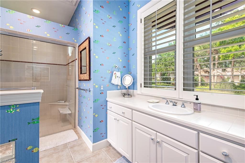7084 Verde Way Naples, FL 34108 - Photo 8 of 18 a spacious bathroom with a granite countertop sink a large mirror and a shower