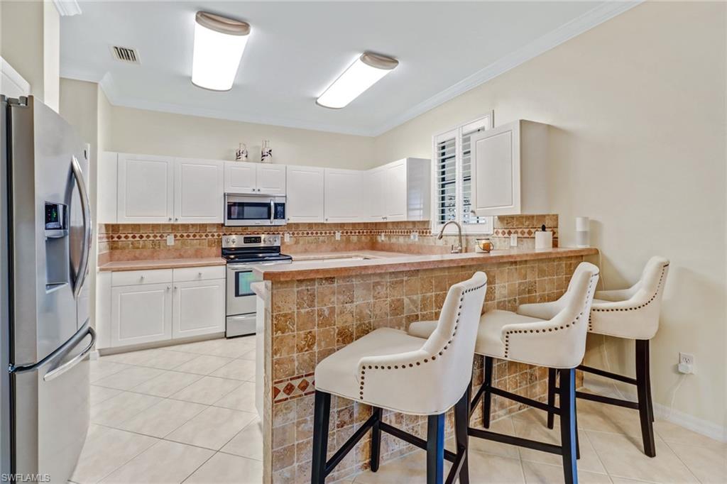 15663 Summit Pl Circle, Unit 328 Naples, FL 34119 - Photo 9 of 32 a kitchen with a dining table chairs and refrigerator