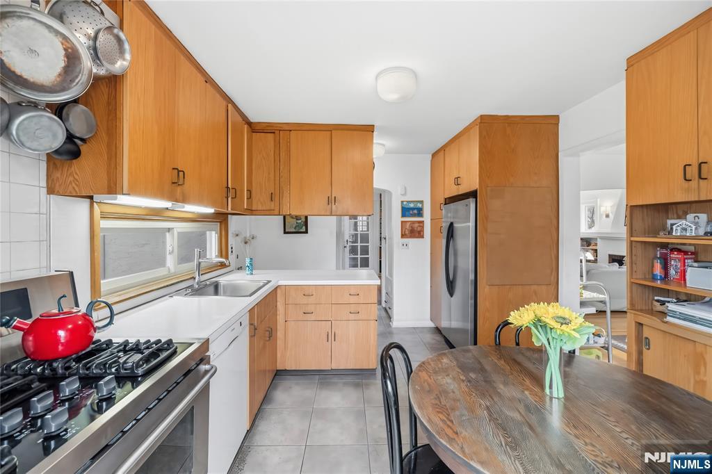 69 Sussex Road Tenafly, NJ 07670 - Photo 18 of 39 a kitchen with stainless steel appliances a stove a sink a refrigerator wooden cabinets and dining table