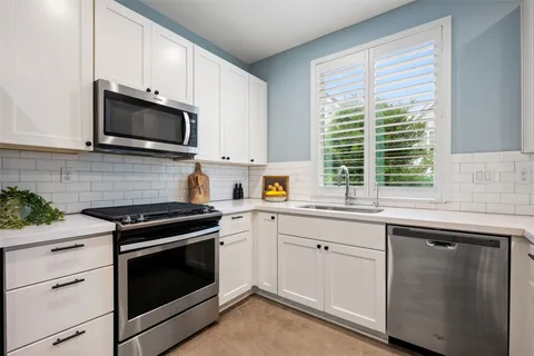 a kitchen with cabinets stainless steel appliances a sink and a window