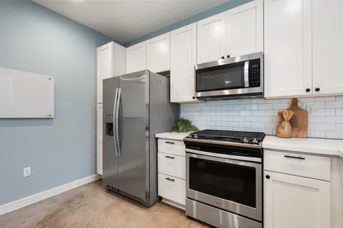 a kitchen with stainless steel appliances white cabinets white stove a microwave and a refrigerator