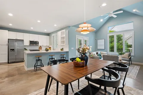 a kitchen with a dining table chairs and refrigerator