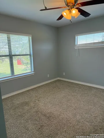 an empty room with a window and a fan