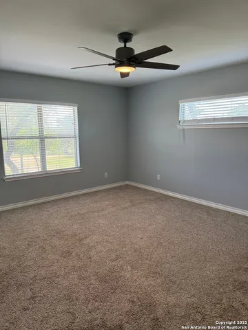 an empty room with windows and ceiling fan