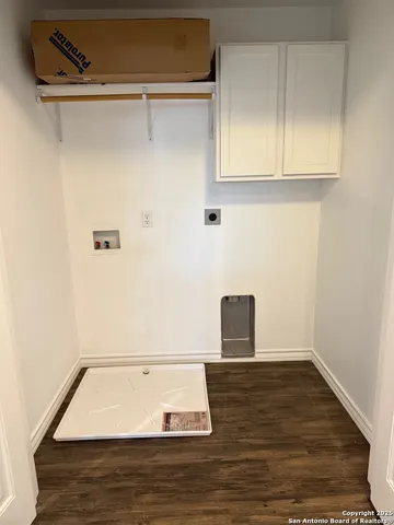 a view of an empty room with wooden floor and cabinets