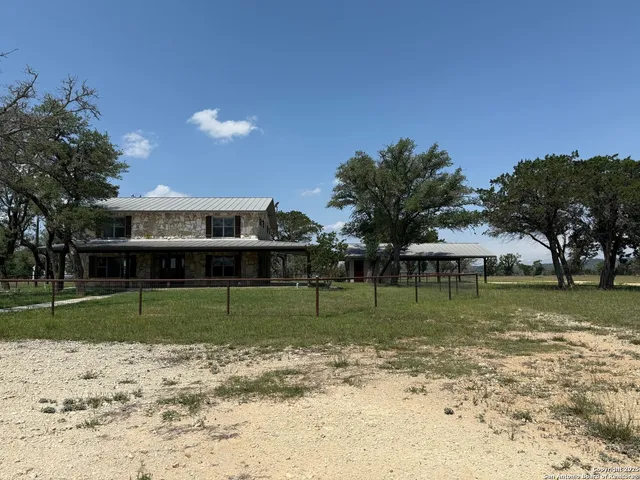 a view of a house with a yard and a large tree