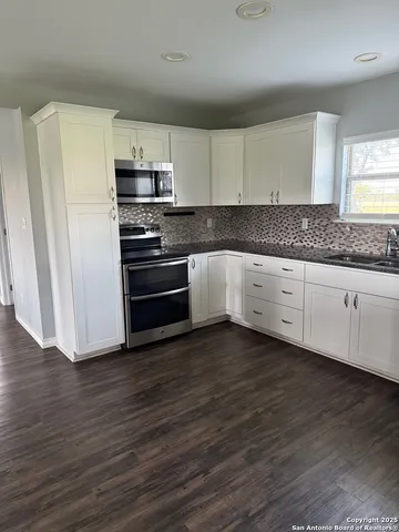 a kitchen with granite countertop white cabinets and stainless steel appliances
