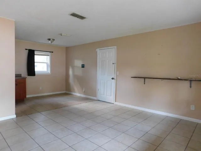 a view of an empty room with window and wooden floor