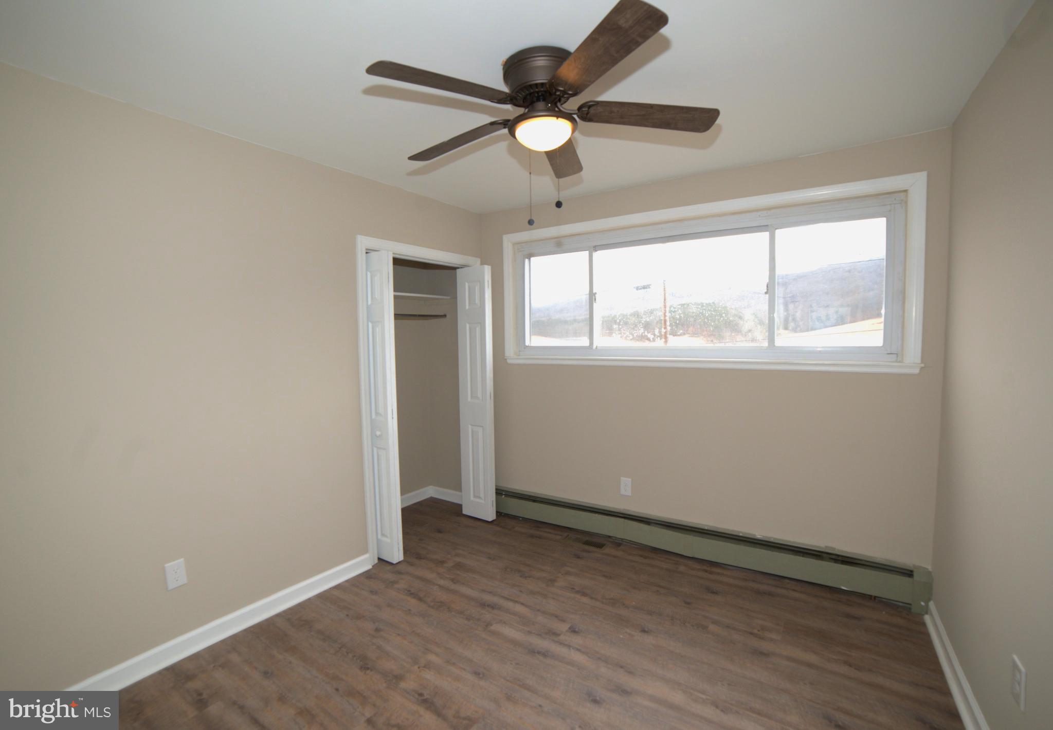 2226 Hyndman Road Hyndman, PA 15545 - Photo 11 of 15 an empty room with wooden floor fan and windows