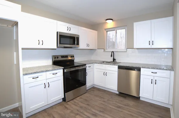 a kitchen with white cabinets and appliances