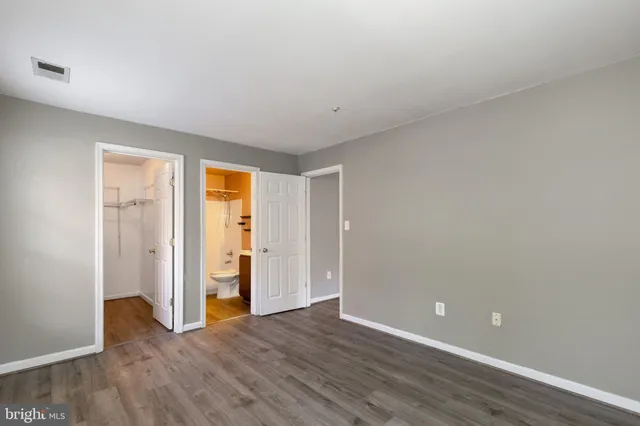 a view of an empty room with wooden floor and closet