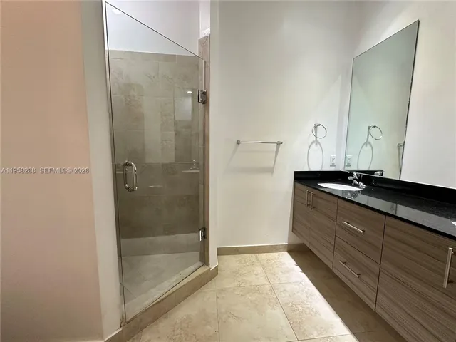 a bathroom with a granite countertop sink a mirror and shower