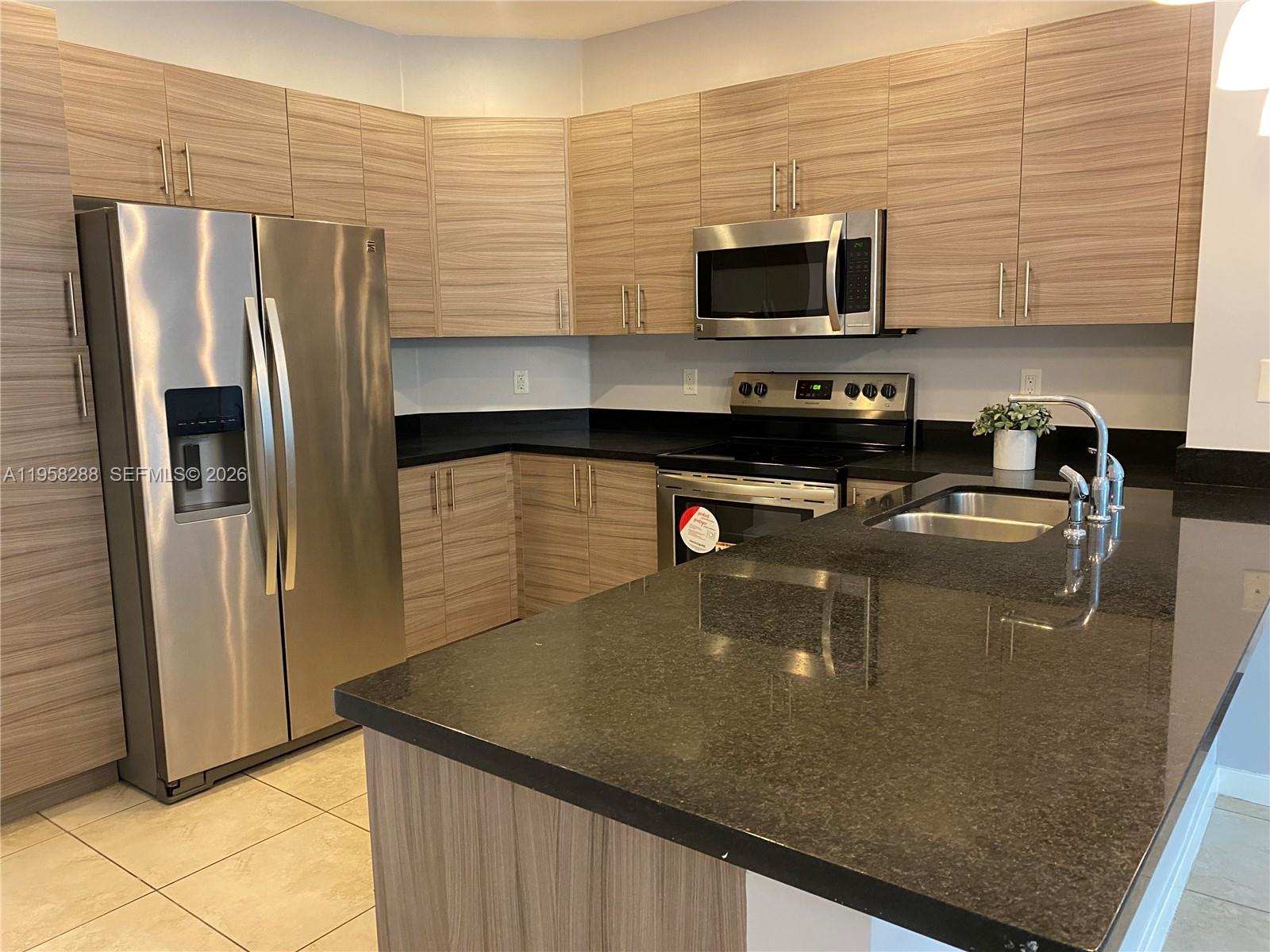 2574 Southwest 81st Terrace, Unit 2564 Miramar, FL 33025 - Photo 6 of 19 a kitchen with stainless steel appliances granite countertop a refrigerator a stove and a sink with wooden floor