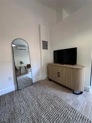 a living room with a flat screen tv on dresser and a table