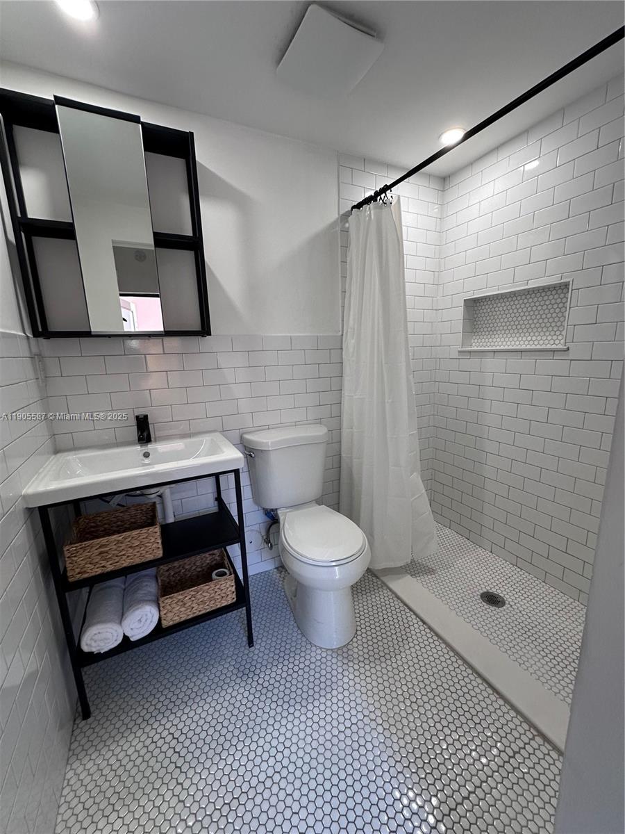 52 Northwest 68th Street, Unit R Miami, FL 33150 - Photo 16 of 19 a bathroom with a toilet a sink and mirror