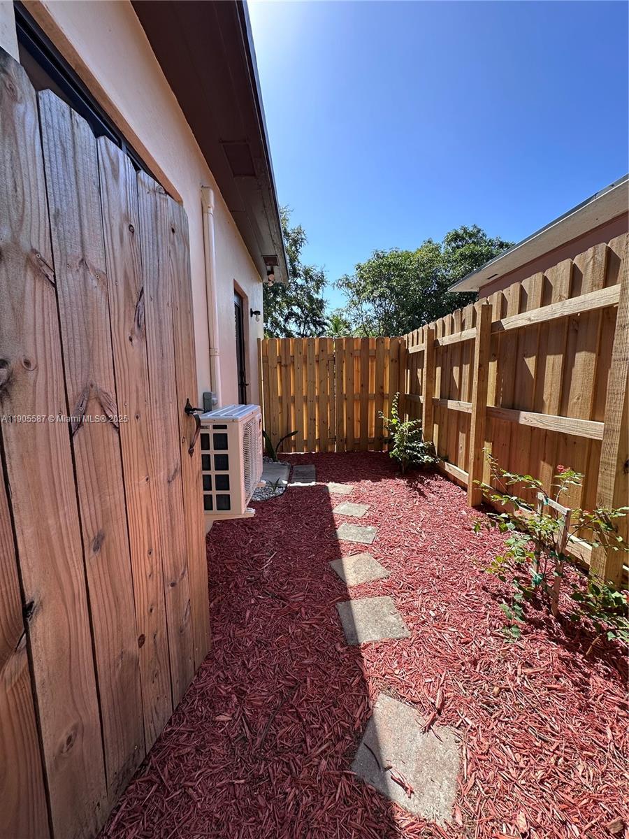 52 Northwest 68th Street, Unit R Miami, FL 33150 - Photo 2 of 19 a view of a backyard with wooden fence and large trees