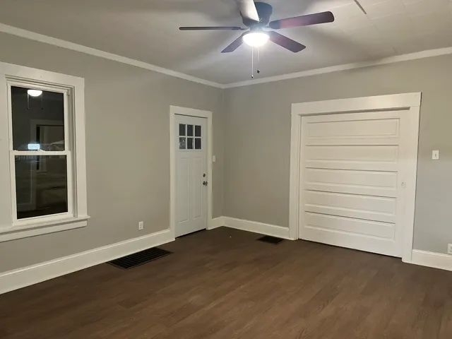 an empty room with wooden floor closet and windows