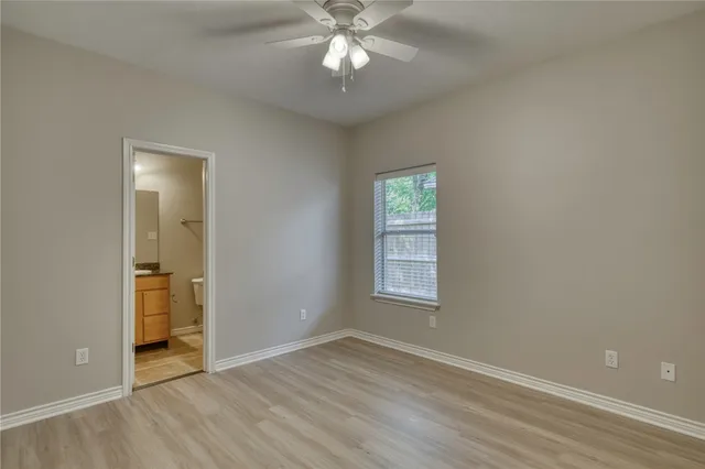 an empty room with wooden floor closet and windows