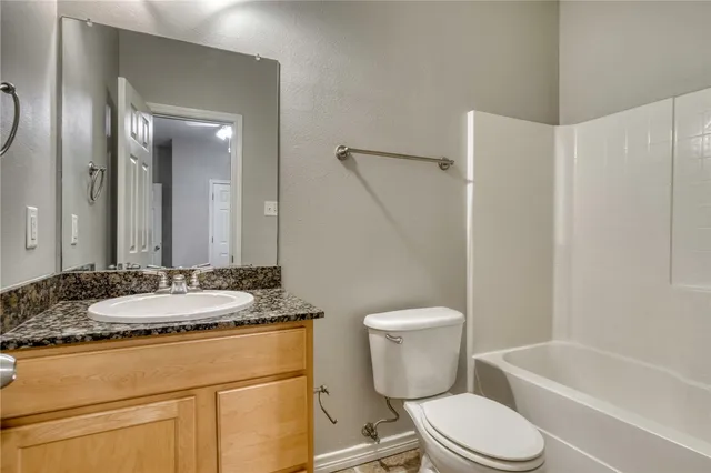 a bathroom with a granite countertop toilet sink and mirror