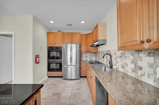 a kitchen with stainless steel appliances granite countertop a sink and a refrigerator