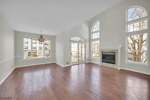 an empty room with wooden floor chandelier and windows
