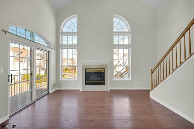 a view of an empty room with wooden floor fireplace and a window