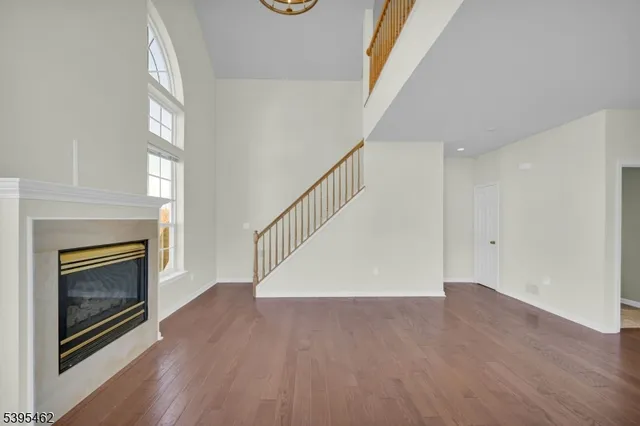 a view of an empty room with wooden floor fireplace and a window