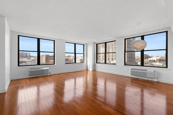 a view of an empty room with window and wooden floor