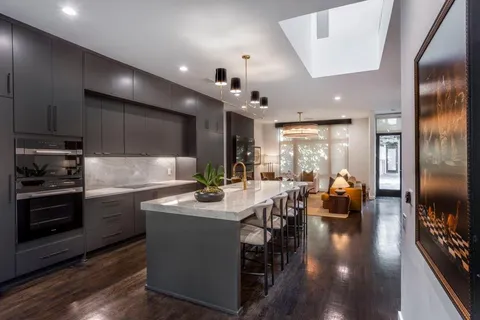 a kitchen with stainless steel appliances kitchen island granite countertop a stove a refrigerator a sink a dining table and chairs with wooden floor